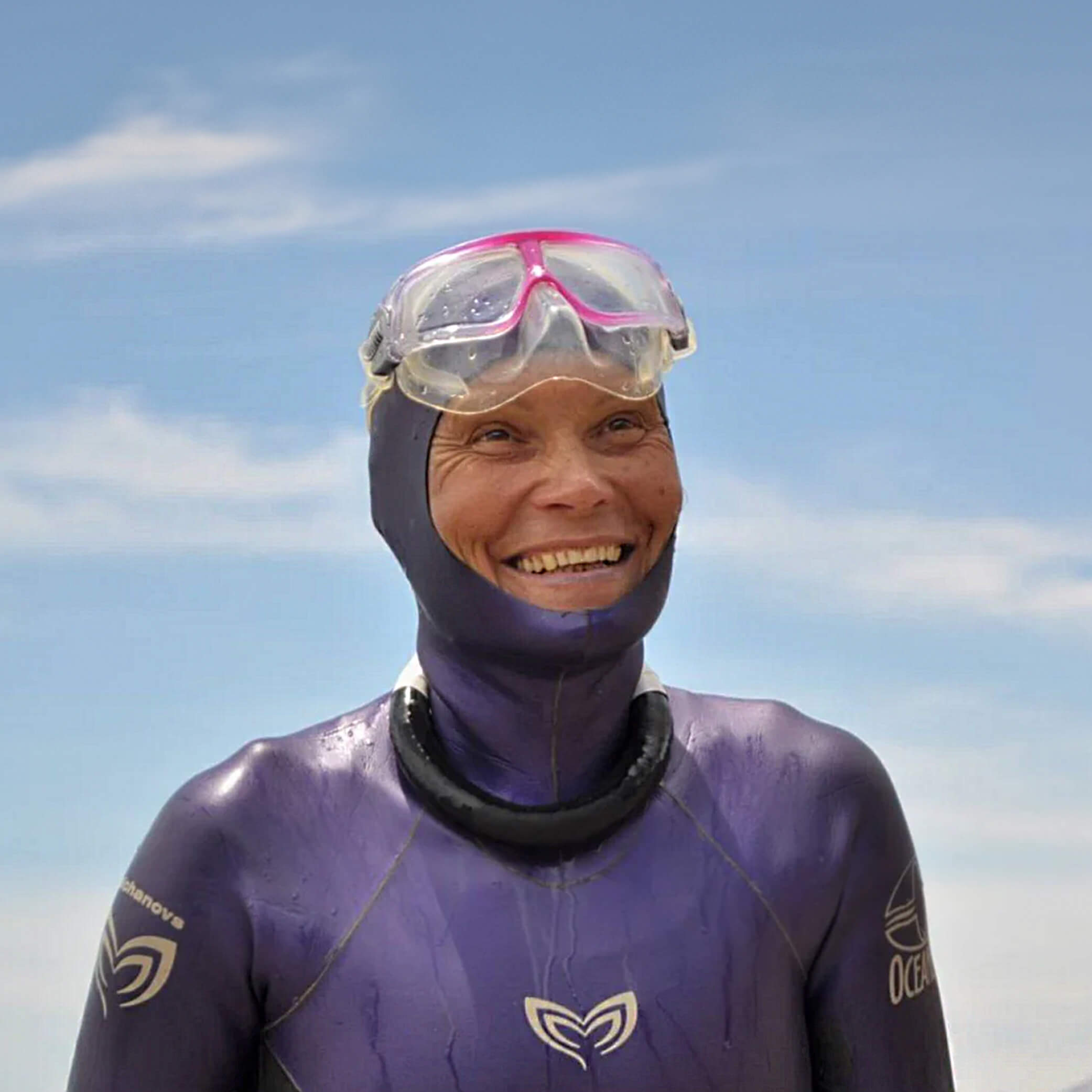 Natalia Molchanova smiling in her purple wetsuit and mask, a moment of joy by the sea